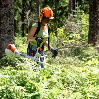 Frau mit einem Freischneider im Wald