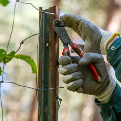 Nahaufnahme einer Hand mit einer Zange beim Zaunabbau