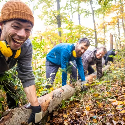 Lachende Teilnehmende beim Anheben eines Baumstammes