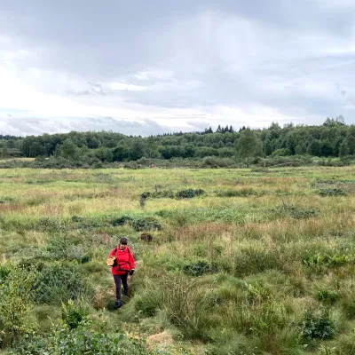 Teilnehmende mit leuchtend roter Jacke in der weiten Landschaft