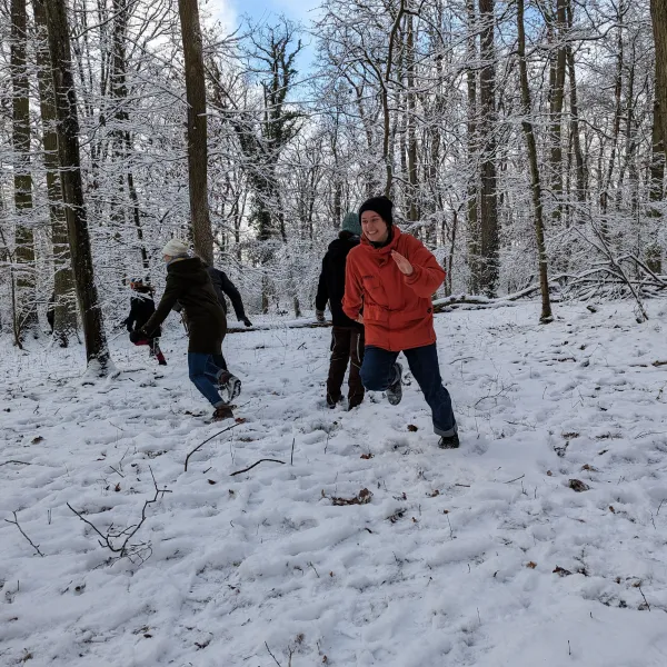 Mehrere Personen spielen ein Spiel im verschneidten Winterwald