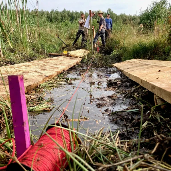 Eine Schnur spannt über einen Entwässerungsgraben im Moor