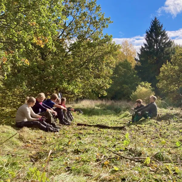 Menschen sitzten auf einer Waldlichtung