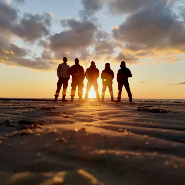 Fünf Menschen stehen vor dem Sonnenuntergang im Kniepsand