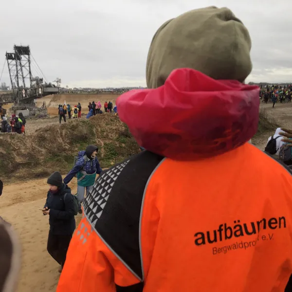 Mensch mit Jacke mit dem Schriftzug "Aufbäumen" steht an einem Tagebau